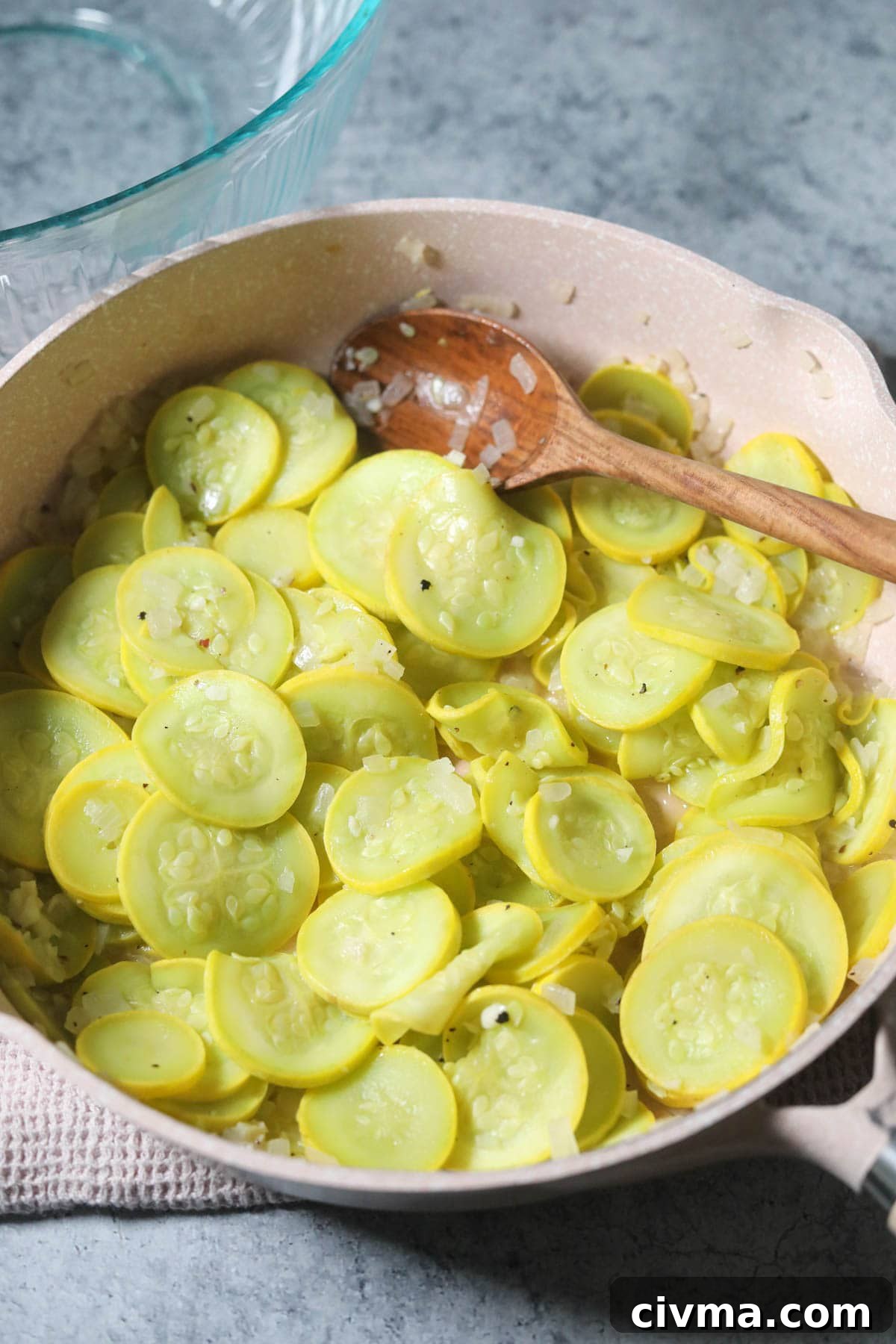 Yellow squash and onion sautéing in a skillet.