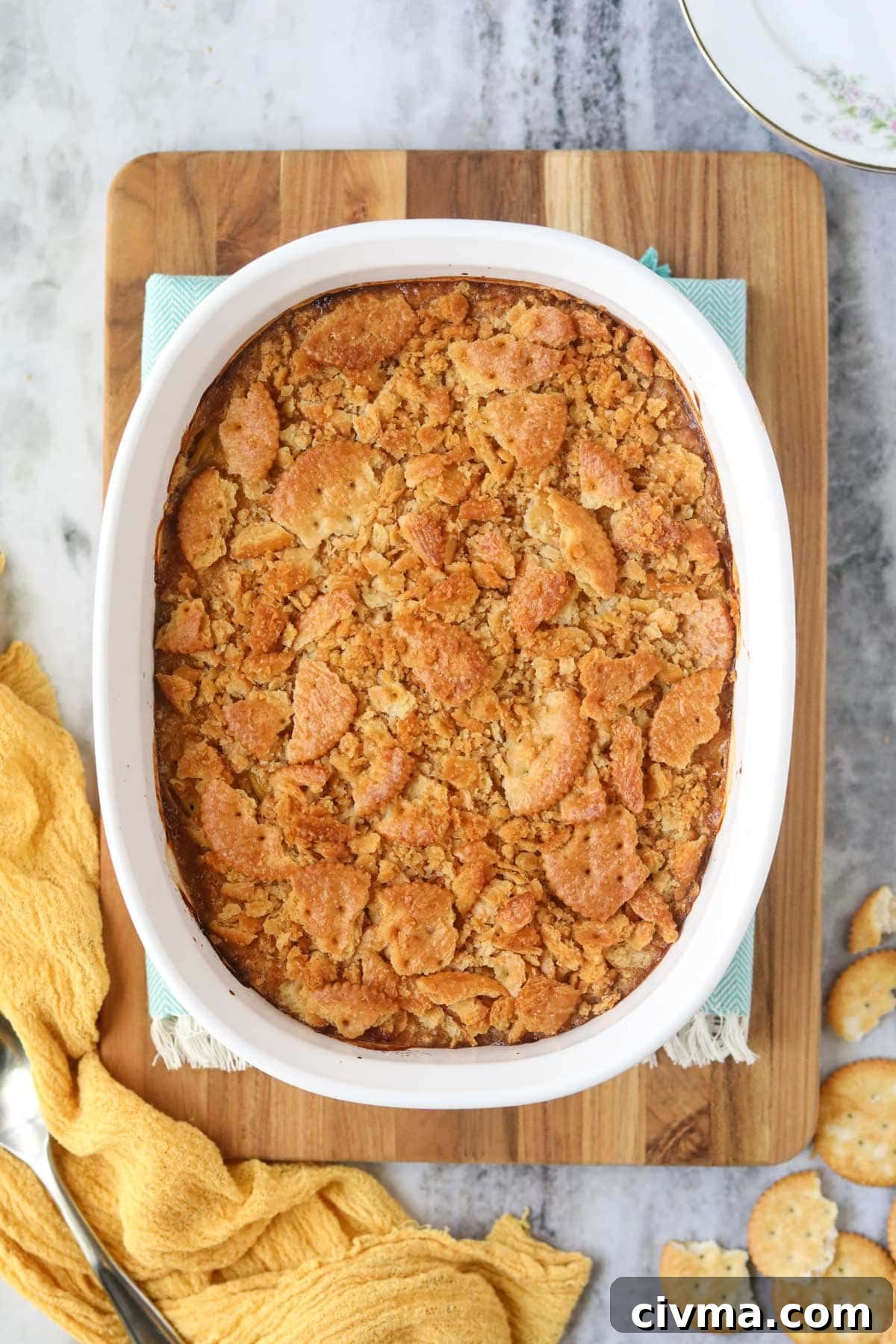 Southern squash casserole and a white baking dish sitting on top of a wooden cutting board.