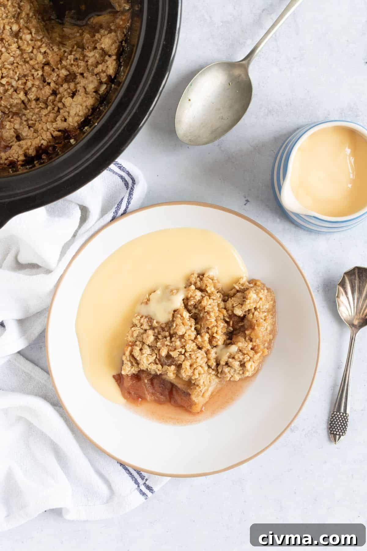 Crock pot apple crumble in a bowl with custard.