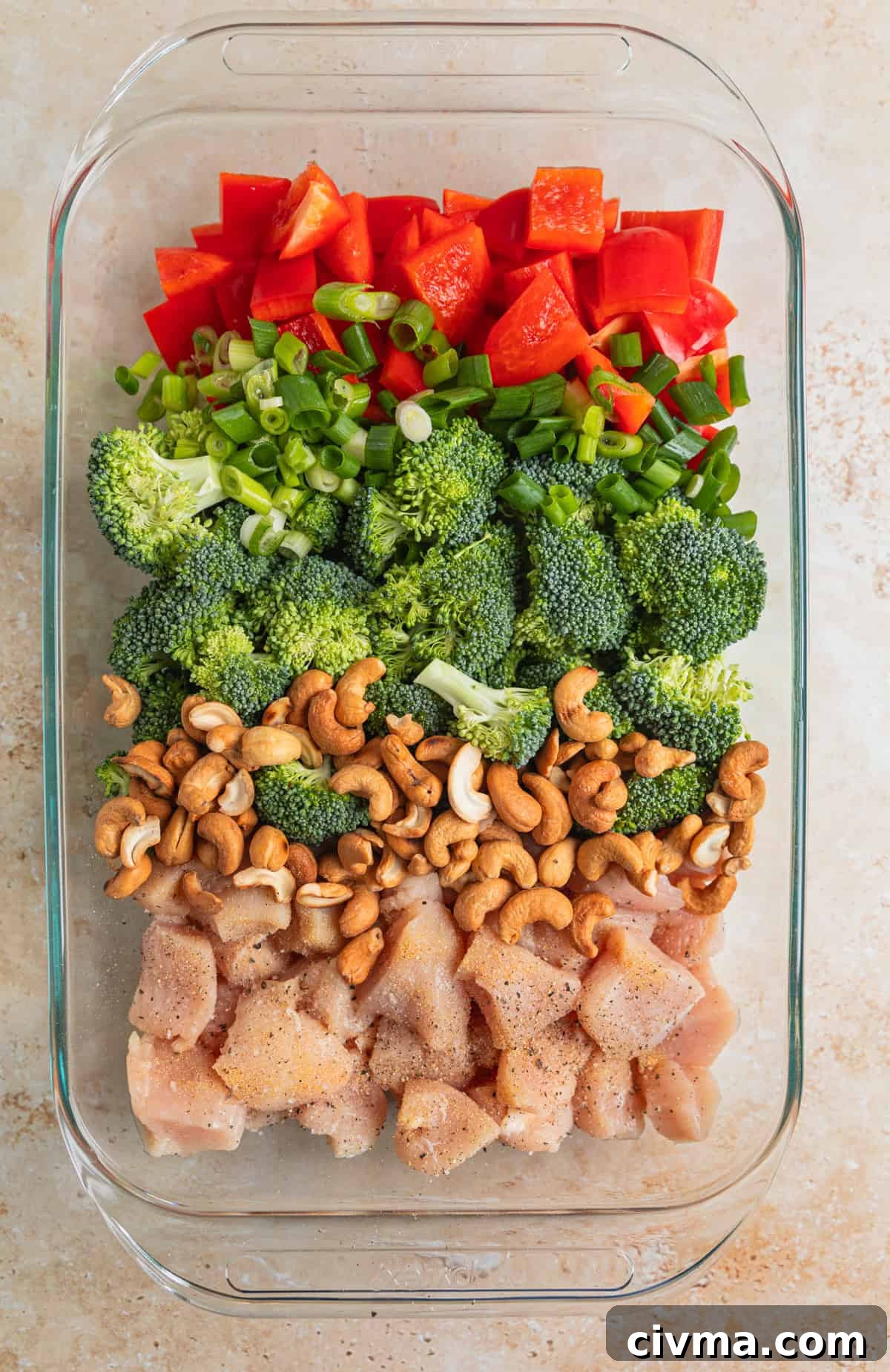 Red bell pepper, broccoli, green onion, cashews and chicken in baking pan.