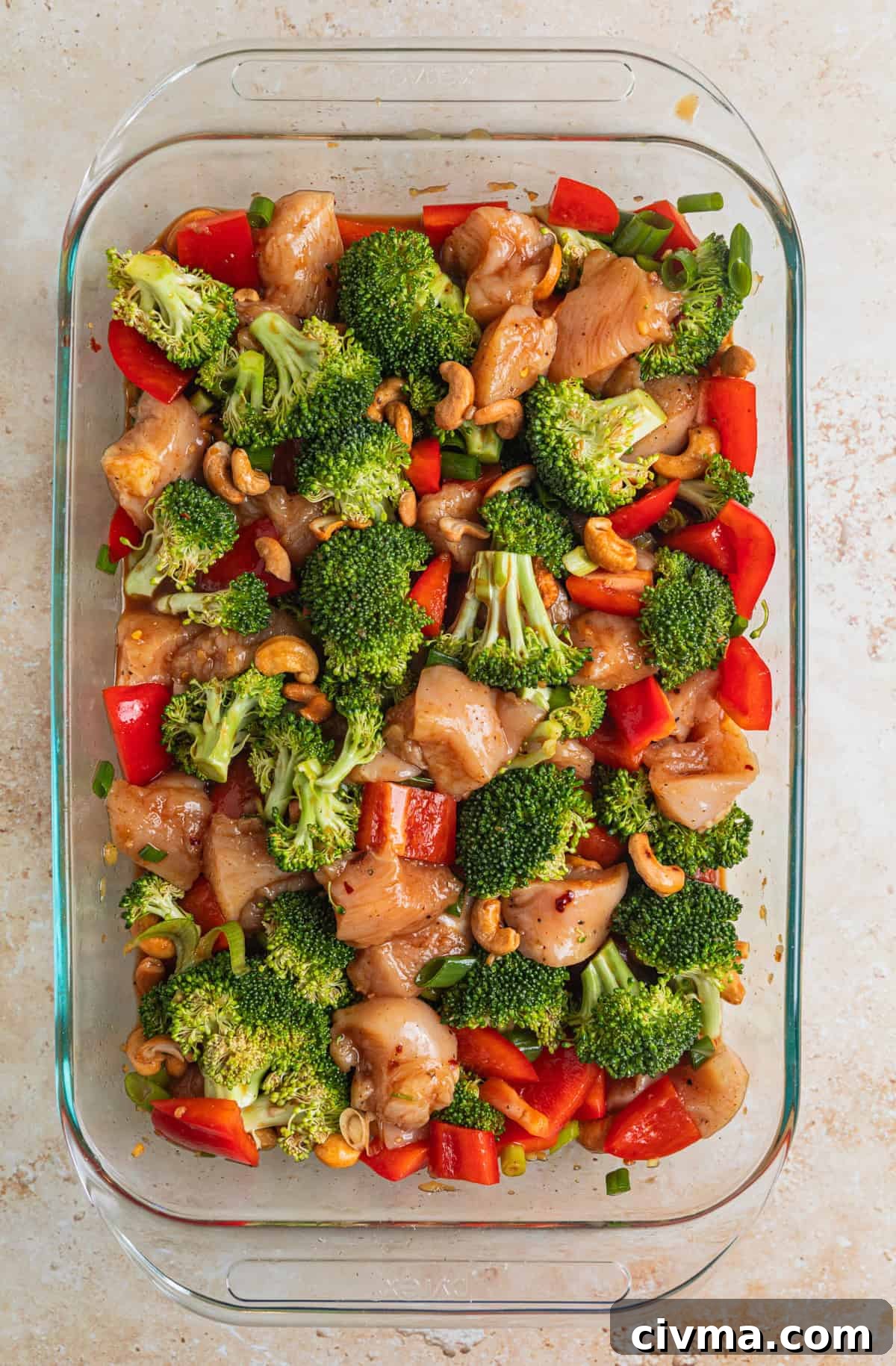 Cashew chicken ingredients in glass pan tossed together in sauce before baking.