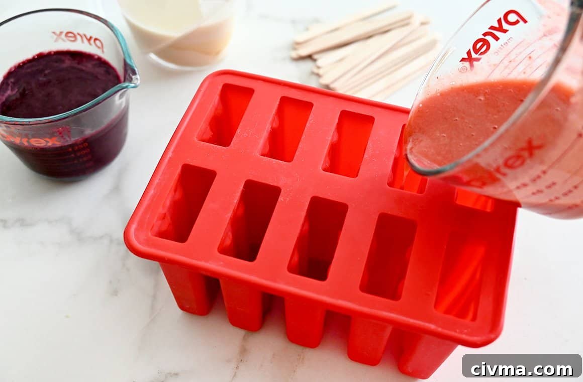 Red White and Blue Fruit Popsicles for the Fourth of July 4 Strawberry puree being poured into a red popsicle mold