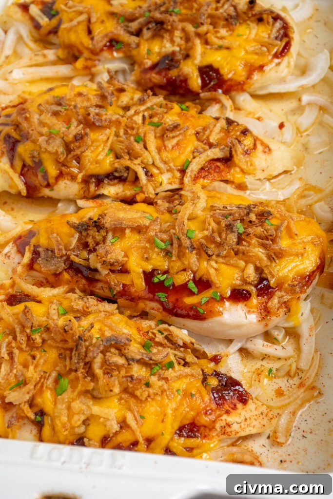 Close up of cheesy BBQ chicken breasts in a white casserole dish.