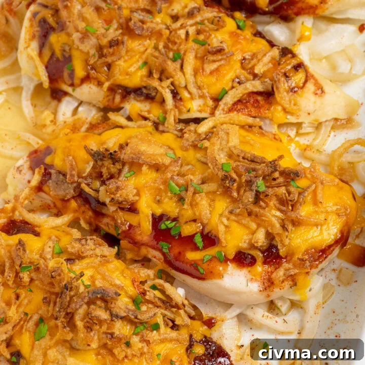 Cheesy BBQ chicken breasts in a casserole dish with melted cheese and crispy fried onions.