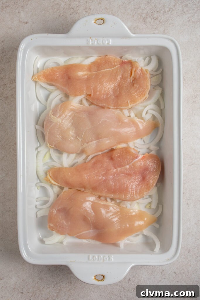Adding four chicken cutlets into a white casserole dish.