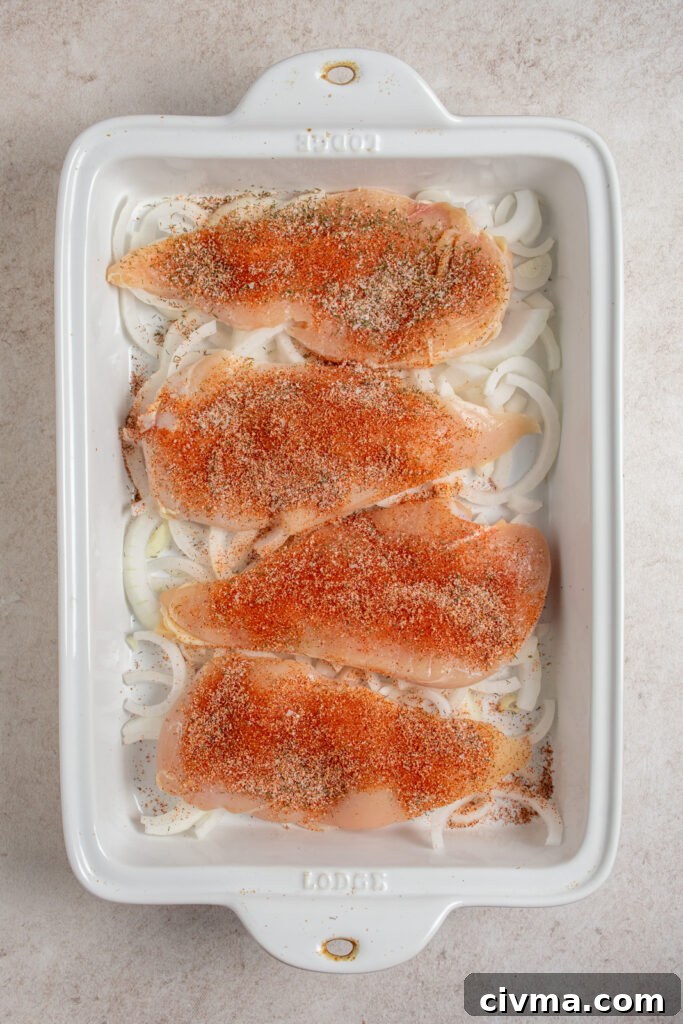 Adding spices to chicken breasts in the casserole dish.