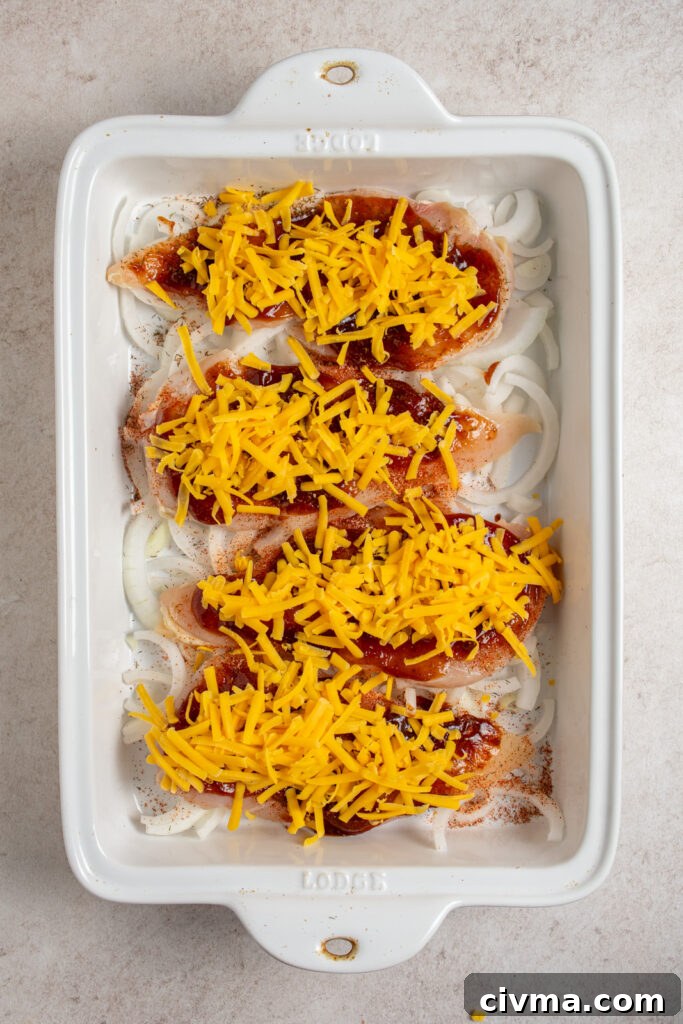 Adding shredded cheddar cheese to chicken breasts in a casserole dish.