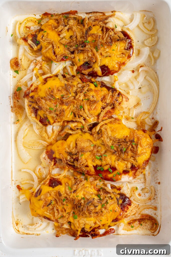 Oven baked cheesy BBQ chicken breasts in a white casserole dish.