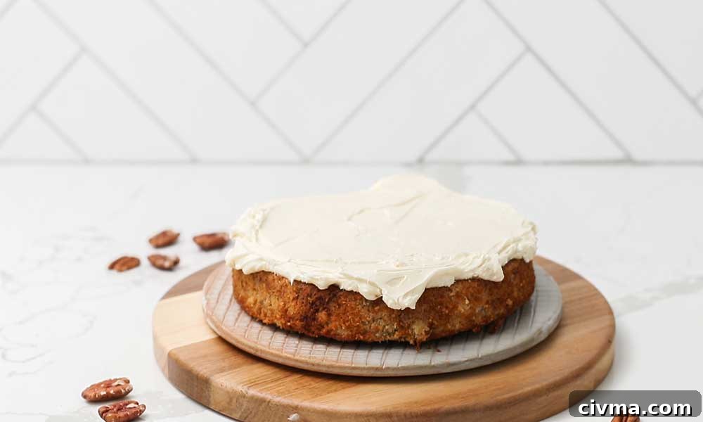 Adding a thick layer of cream cheese frosting onto the top of the first layer.