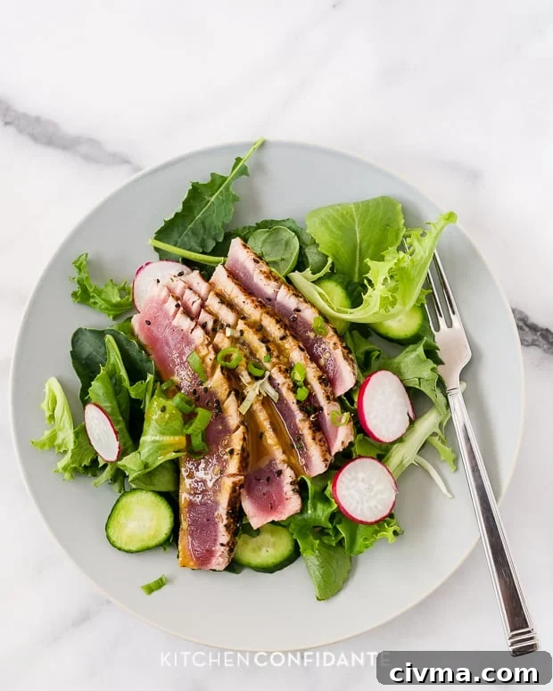Seared Ahi Tuna Salad | Kitchen Confidante Slices of seared ahi tuna on a plateful of greens, sliced cucumbers, and sliced radishes.