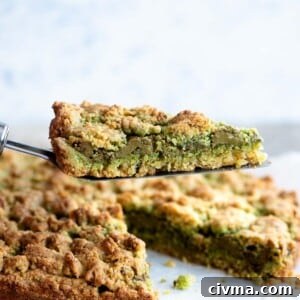 A close cup of a slice of pistachio crumb cake being help up on a cake server.
