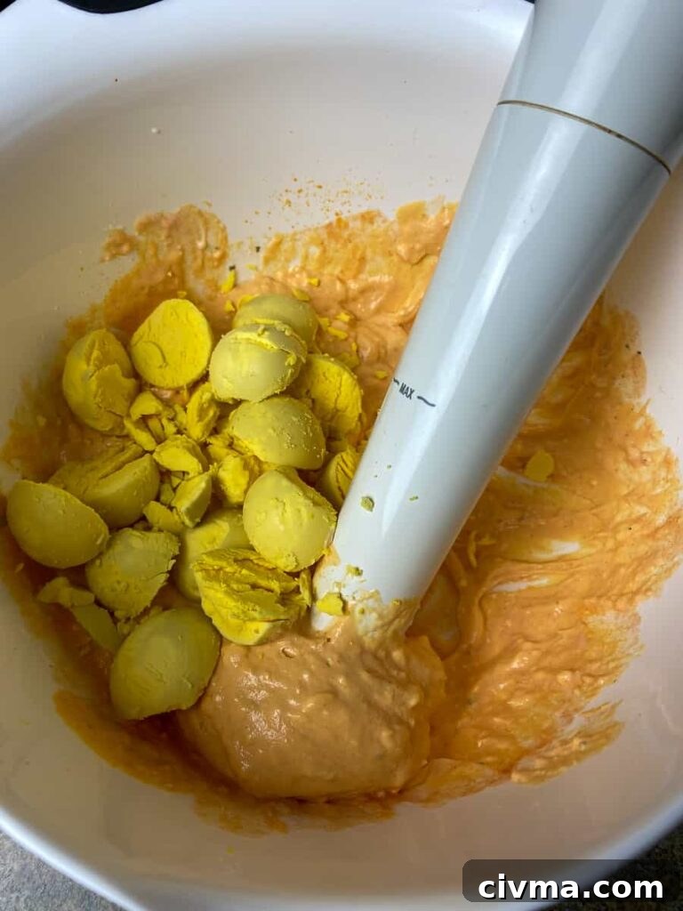Adding egg yolks to mixing bowl