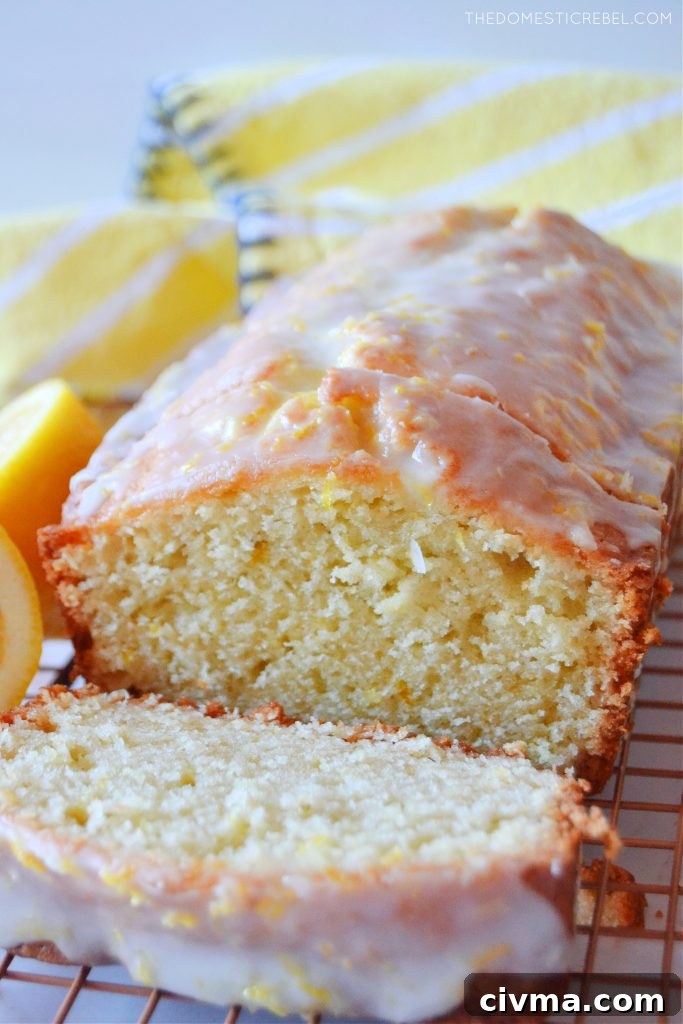 lemon loaf cake with a slice cut off and a yellow cloth in the background