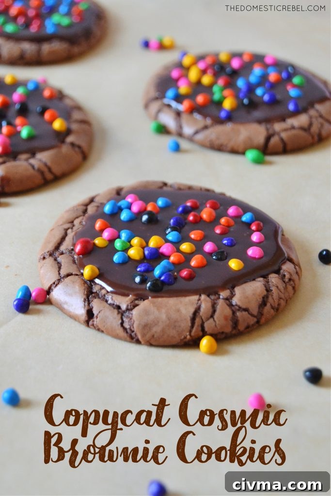cosmic brownie cookies arranged on parchment paper with sprinkles in the background