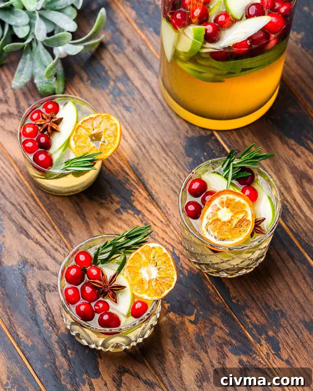 Table with 3 glasses of Christmas sangria along with pitcher.
