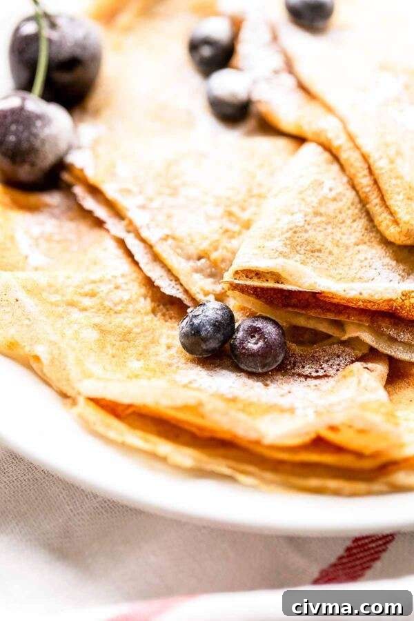 Authentic French Crepes Recipe 8 Close up of tasty French crepes with blueberries and cherries on top.