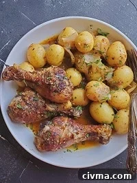 chicken drumsticks and potatoes served in a white plate with a spoon