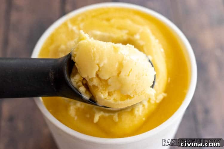 Creamy Mango Coconut Ice Cream Recipe 11 ice cream scooping lifting up some of the mango coconut ice cream