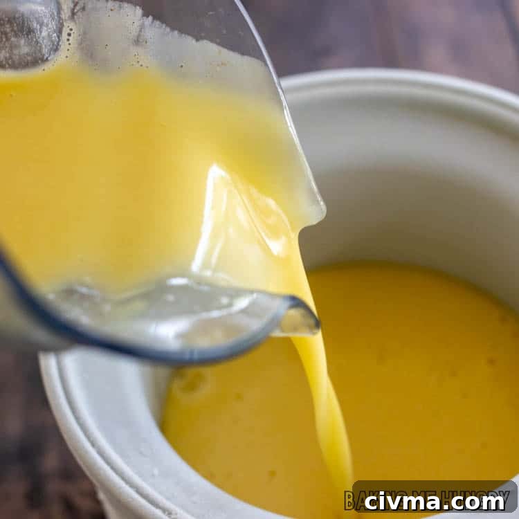 Creamy Mango Coconut Ice Cream Recipe 7 orange liquid being poured into freezer bowl