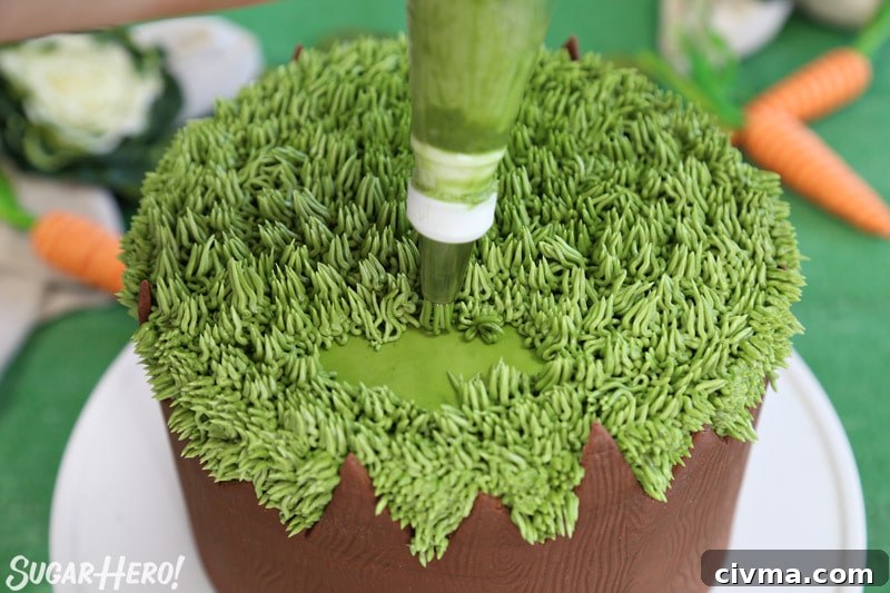 Piping green buttercream onto the top of the cake with a grass piping tip