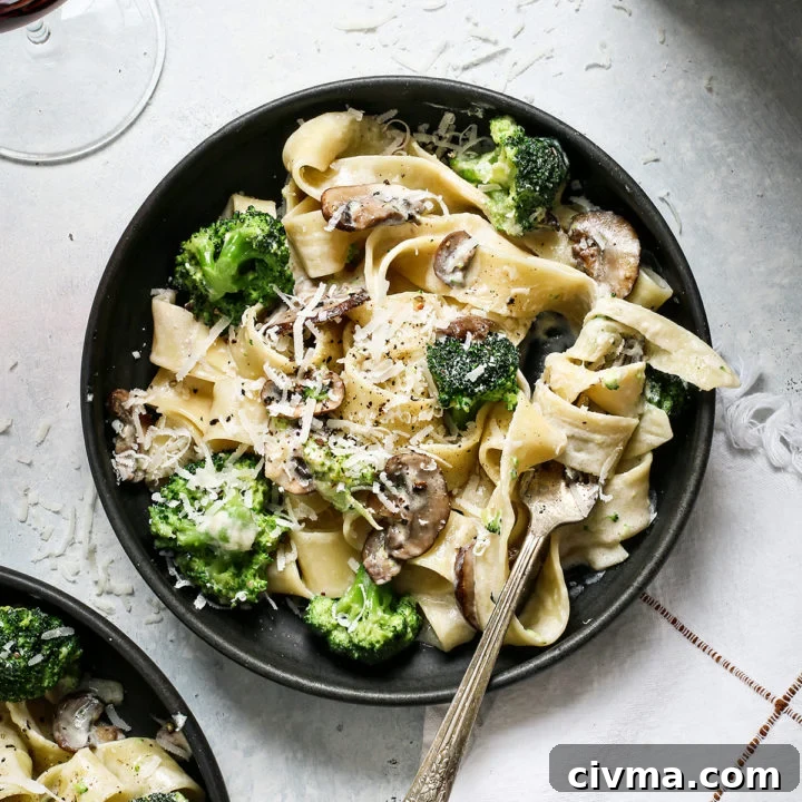 two pasta bowls with mushroom alfredo next to a glass of wine