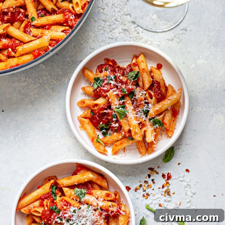 two plates of penne arrabbiata and a glass of wine