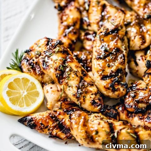 close up photo of grilled chicken tenderloins on a white platter