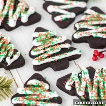 Nutella Stuffed Cookies Recipe 9 Chocolate sugar cookies decorated with icing and sprinkles on white board.