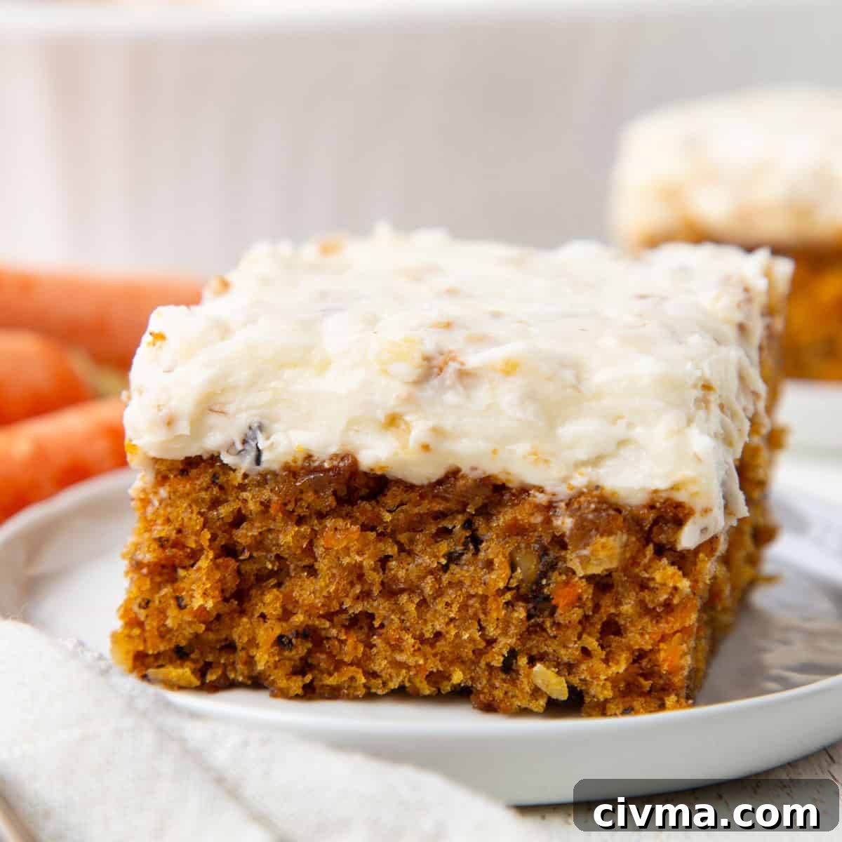 slice of carrot cake with a thick white cream cheese frosting with coconut inside on top.