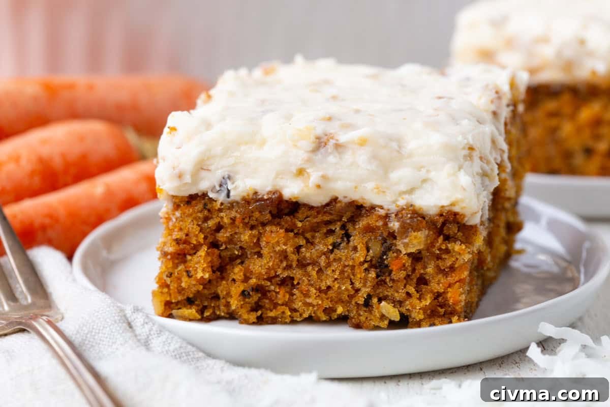 square slice of carrot cake with a coconut cream cheese frosting spread on top.