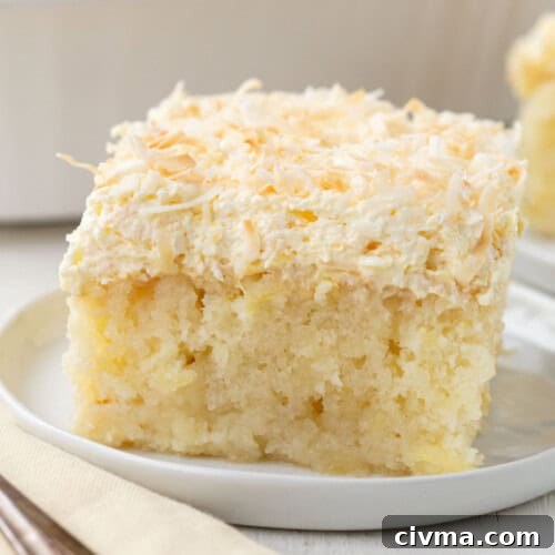 slice of yellow cake topped with toasted coconut on a white plate.