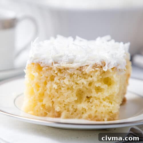 coconut poke cake slice on a white plate.