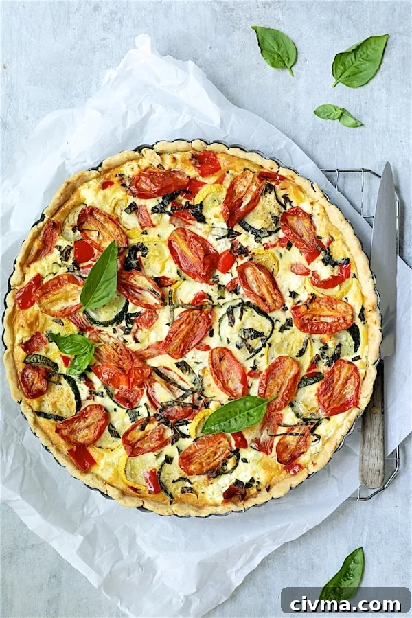 Photo of baked Provencal Vegetable and Goat Cheese Tart on parchment paper garnished with fresh basil.