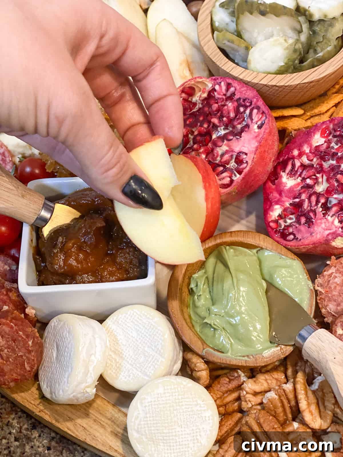 Create a Stunning Thanksgiving Charcuterie Board 8 Hand dipping apple slice into pistachio cream