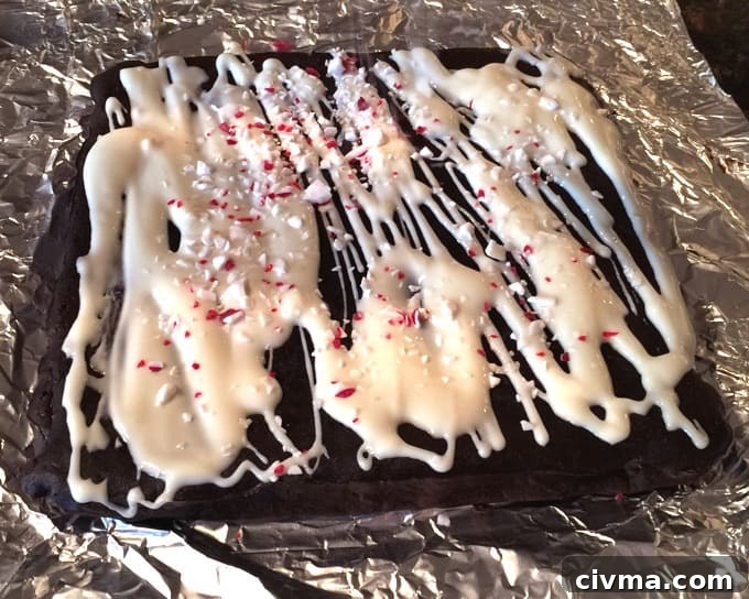 Fresh baked Peppermint Chocolate Cookie Bars drizzled with icing and crushed candy canes sitting on tin foil.