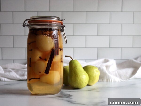 Homemade pickled pears in a jar on a white countertop.