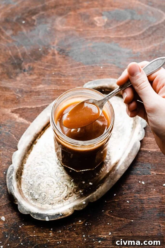 Salted Caramel Apple Pie Cookie Recipe 6 A spoon dipping into a jar of caramel sauce.
