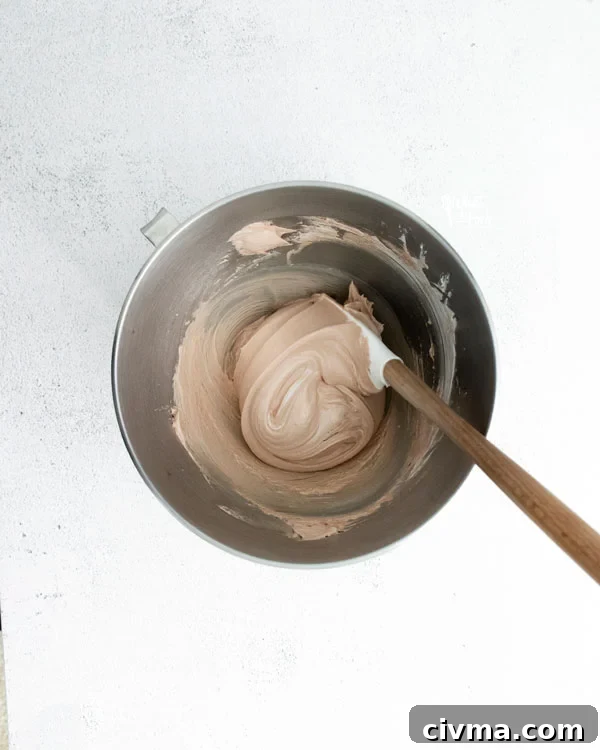 overhead shot of dark chocolate meringue cookie batter in a silver bowl with a spatula