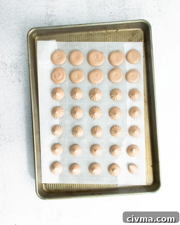 dark chocolate meringue cookies piped onto a parchment lined baking sheet ready to go in the oven