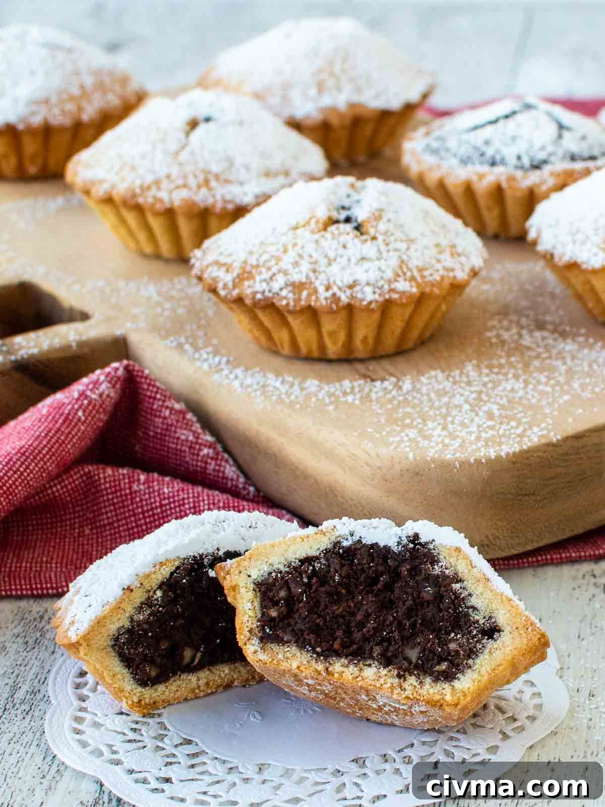 Bocconotti: Italian Chocolate-Almond Pastries from Puglia 2 Bocconotti on a wooden board with one cut in half at the front on a paper doiley.