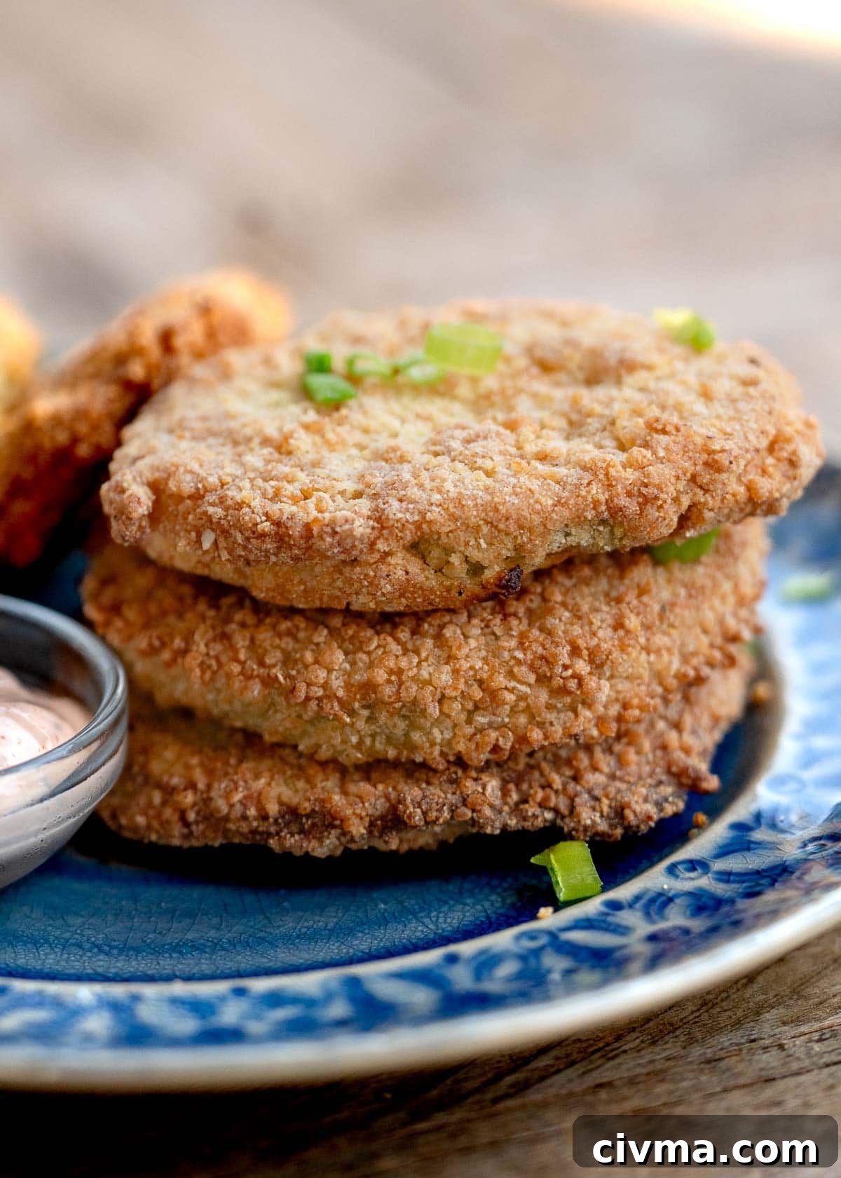 a stack of three crunchy fried green tomatoes on a plate with a side of sauce
