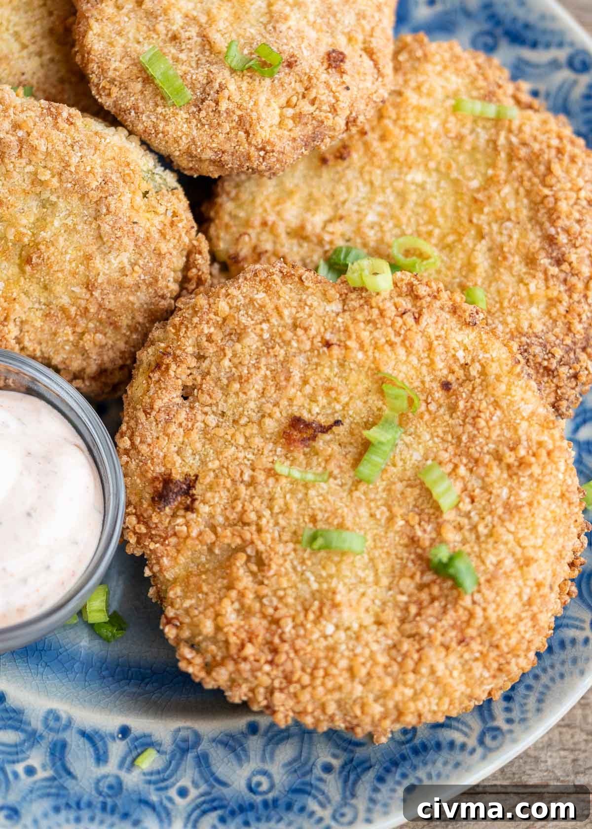 a blue plate full of crispy air fryer fried green tomatoes with a side of dipping sauce