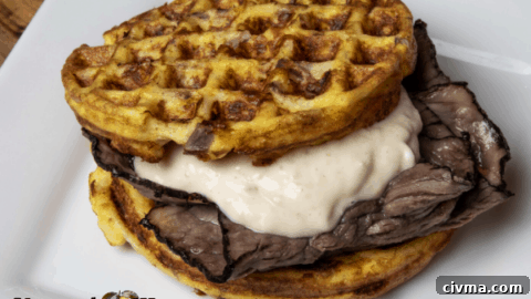 Onion Chaffle with roast beef and sauce on a white plate