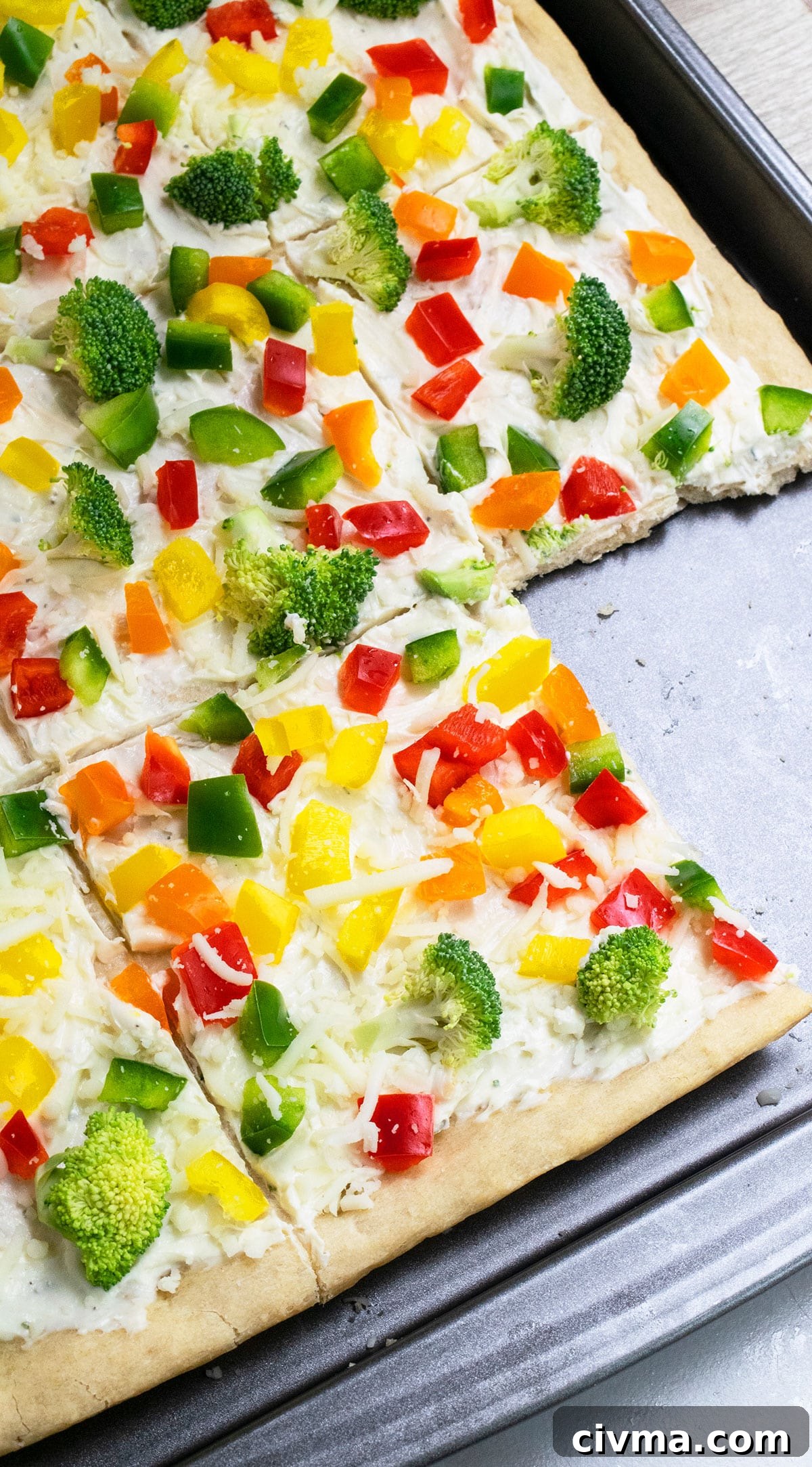 Easy cold crescent roll veggie pizza with ranch on baking tray with one slice removed.