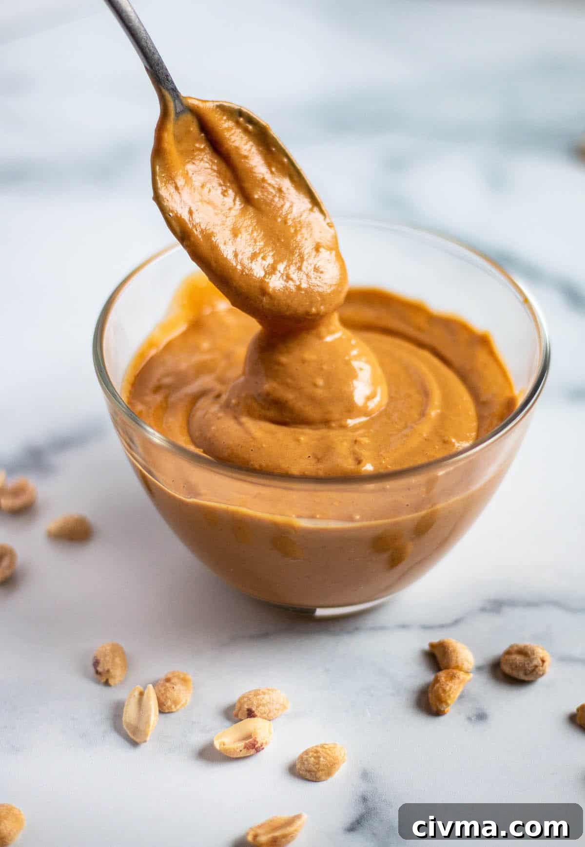 A bowl with a peanut sauce and spoon. 