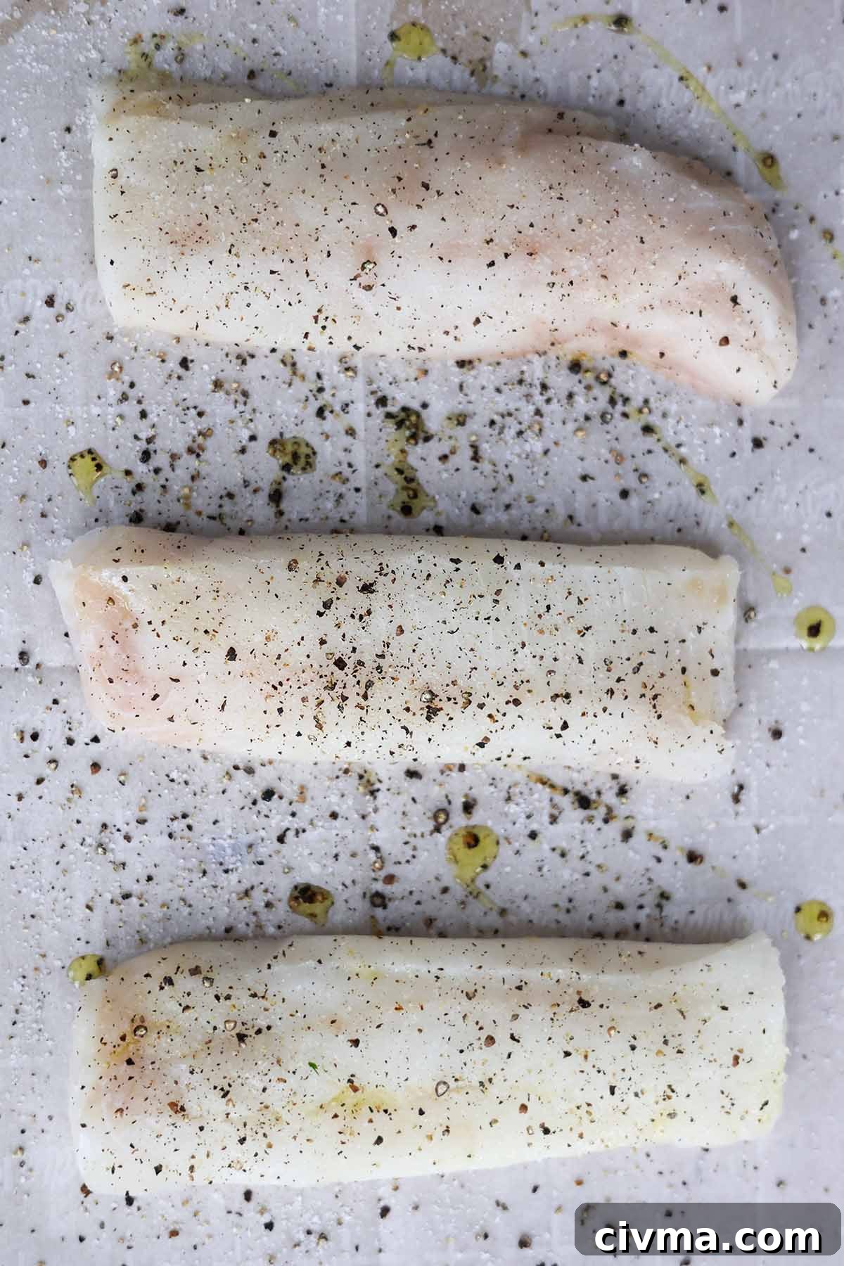 Baked Cod with Chimichurri Sauce 4 Three raw cod fish fillets seasoned with salt and pepper on a baking sheet.