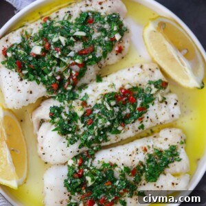 Baked Cod with Chimichurri Sauce 6 Three cod fillets with chimichurri on top and lemon wedges on the side.