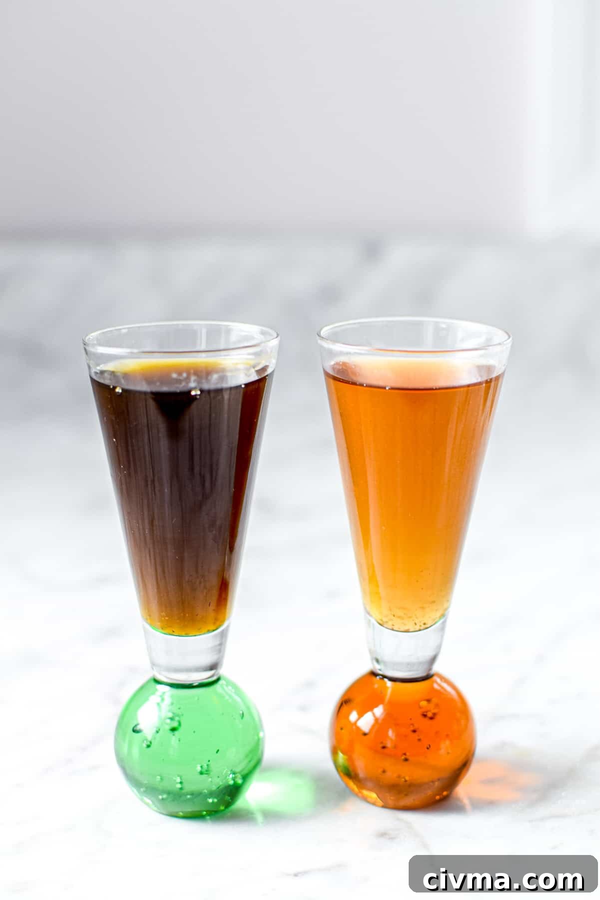 Two shot glasses full of liquid, the first much darker, the second a golden color, comparing the Green Dragon vs Golden Dragon tinctures