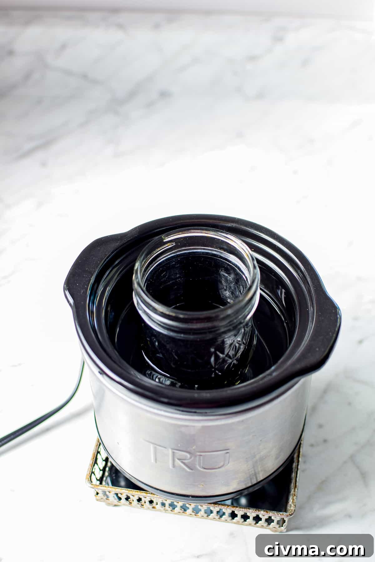 A white countertop with a small warming crockpot with a mini mason jar inside