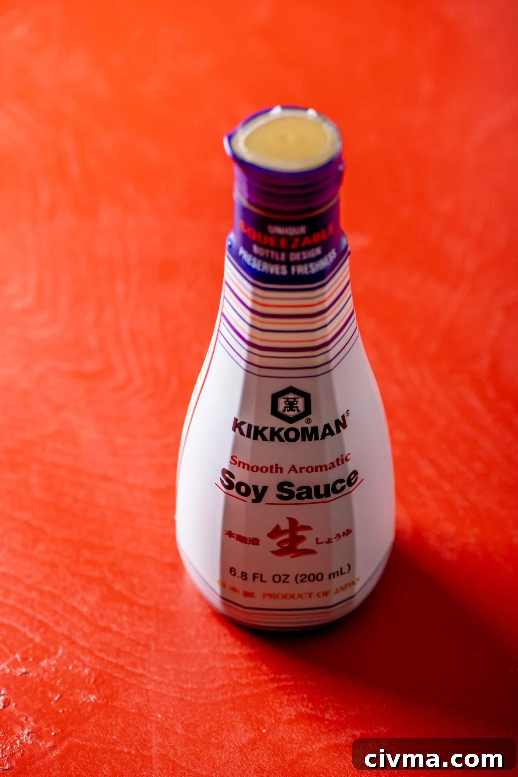 Jar of Kikkoman Soy Sauce on red table.